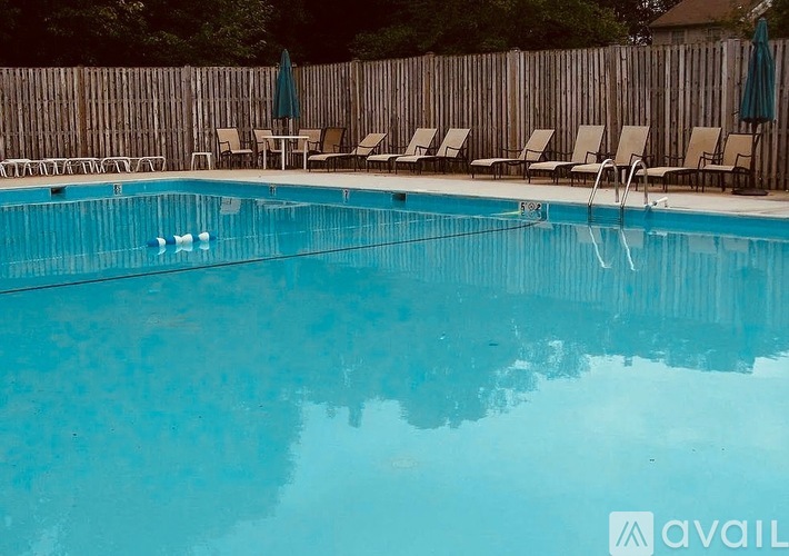 A pool with chairs and umbrellas around it.