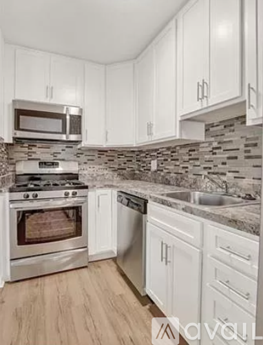 A kitchen with white cabinets and a stone backsplash.