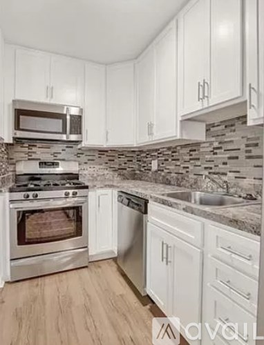A kitchen with white cabinets and a stone backsplash.