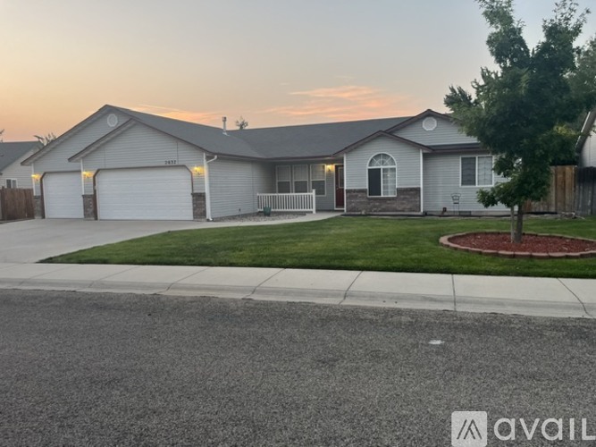 A house with a garage and a tree in front of it.