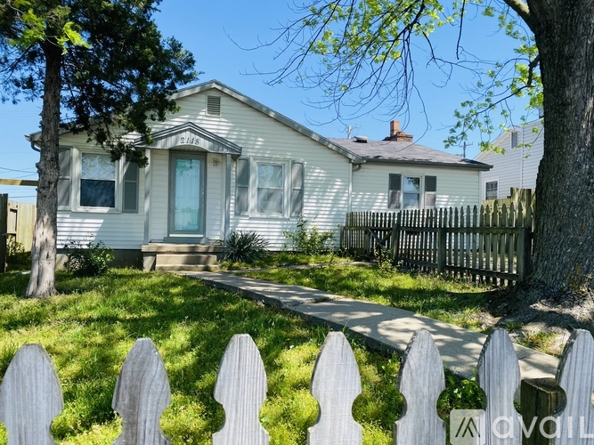 A white house with a picket fence in front of it.