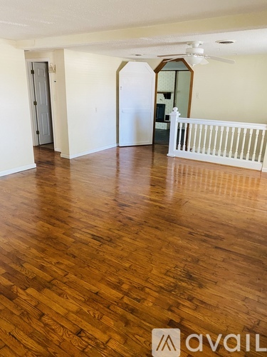 A room with wooden flooring and a white railing.