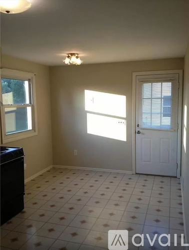 A room with a white door, a window with blinds, and a tiled floor.