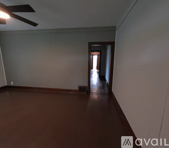 A room with a brown floor and a ceiling fan.