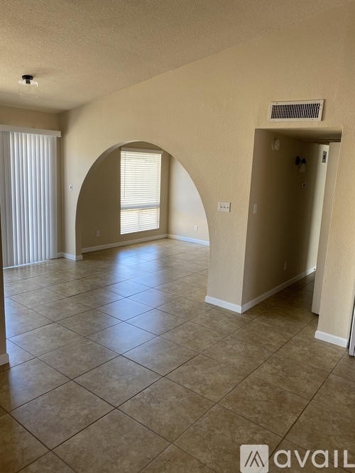 A spacious room with beige walls and a tiled floor.