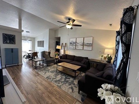 A living room with a brown couch and a ceiling fan.
