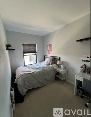 A bedroom with a bed, desk, and window.