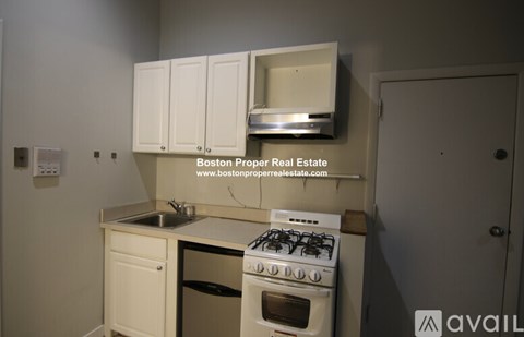 A kitchen with a stove, sink, and cabinets.