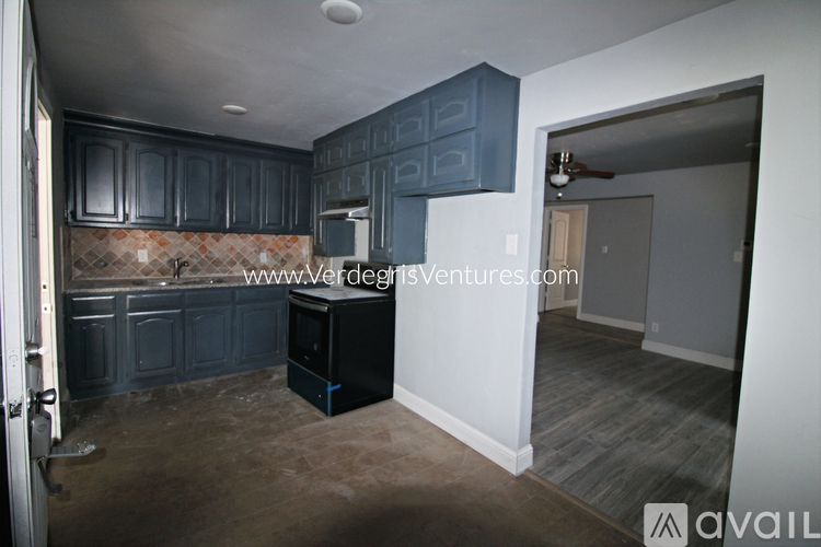A kitchen with dark blue cabinets and a black refrigerator.