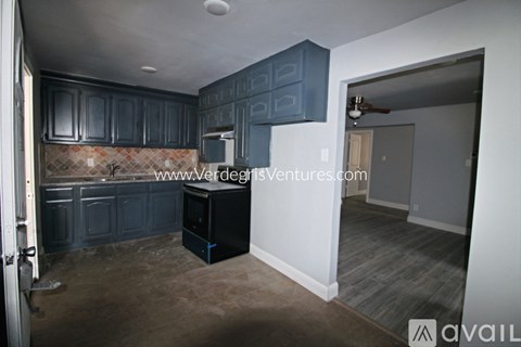 A kitchen with dark blue cabinets and a black refrigerator.
