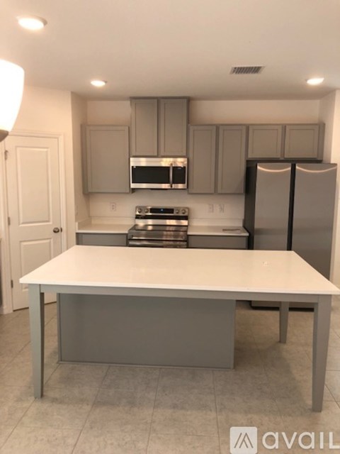 A kitchen with a white table and grey cabinets.