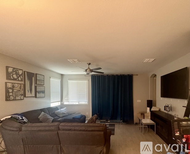 A living room with a couch, a television, and a ceiling fan.