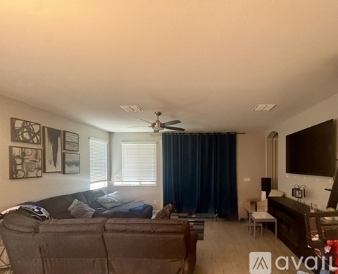 A living room with a couch, a television, and a ceiling fan.