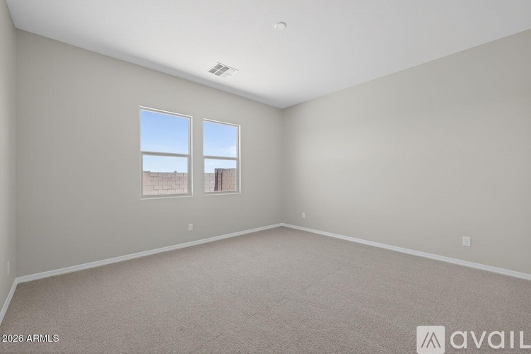 A spacious room with carpeted floor and two windows.
