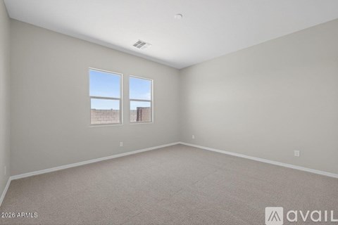 A spacious room with carpeted floor and two windows.