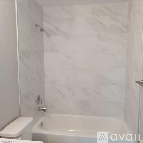 A white bathroom with a tub and toilet.