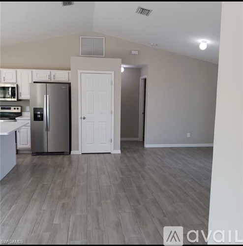 A kitchen with a refrigerator, microwave, and oven.