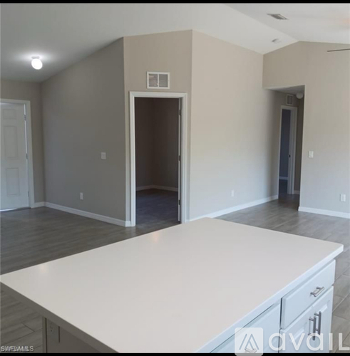 A large white countertop in a room with a doorway leading to another room.