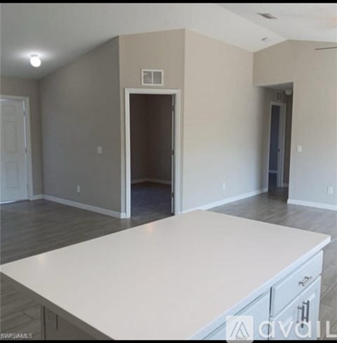 A large white countertop in a room with a doorway leading to another room.