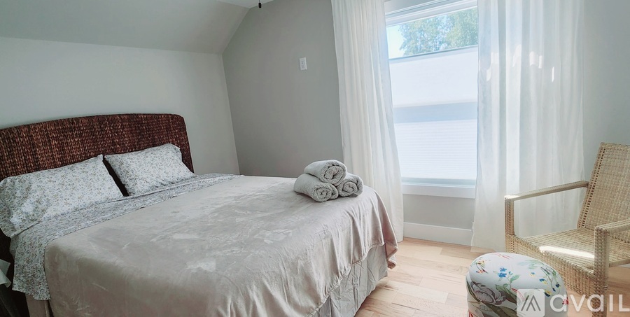 A bedroom with a bed, chair, and window.