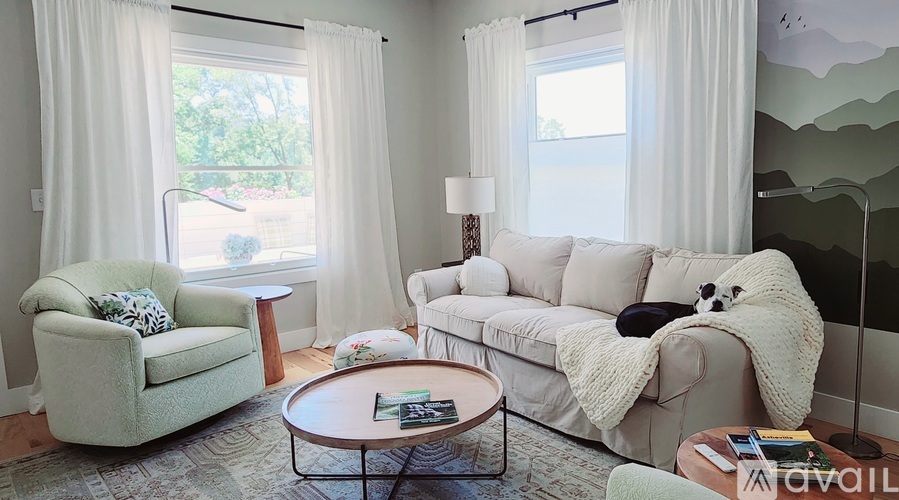 A living room with a white couch, a green armchair, and a coffee table.