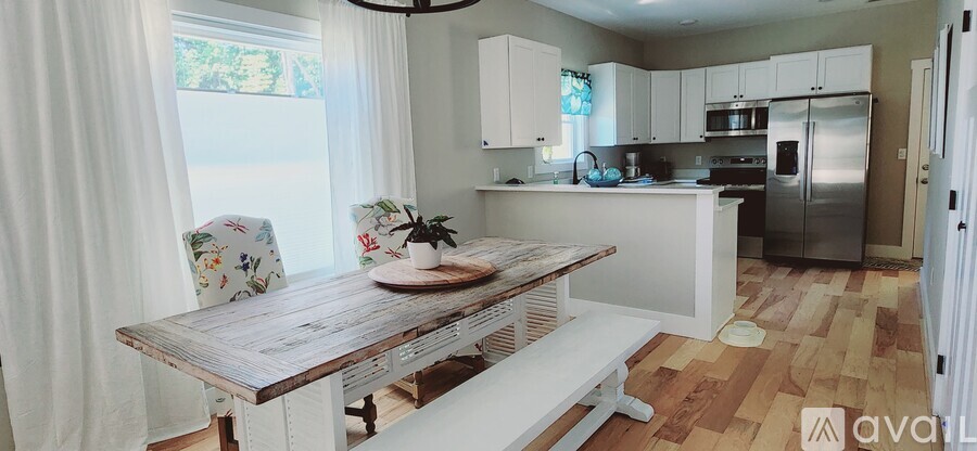 A kitchen with a wooden table and white chairs.