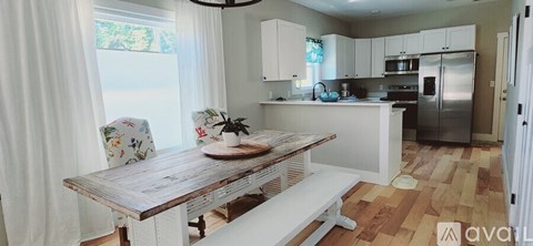 A kitchen with a wooden table and white chairs.