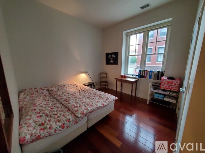 A bedroom with a bed, desk, chair, and window.