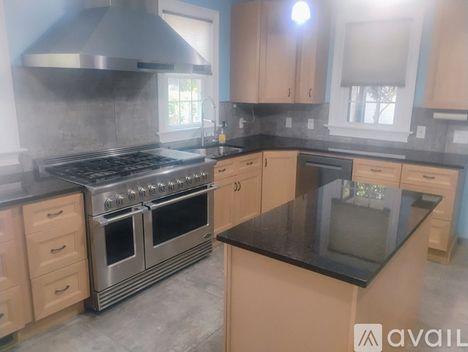 A kitchen with a black countertop and a stainless steel range hood.