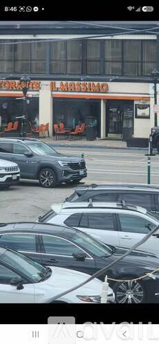 A parking lot with several cars and a building with a sign that reads "FORARE L'MISSIMO".