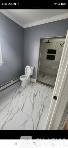 A bathroom with a toilet and a marble floor.