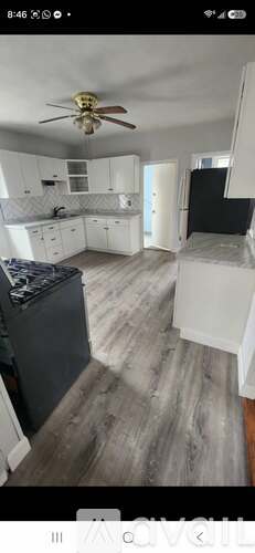 A kitchen with white cabinets and a ceiling fan.