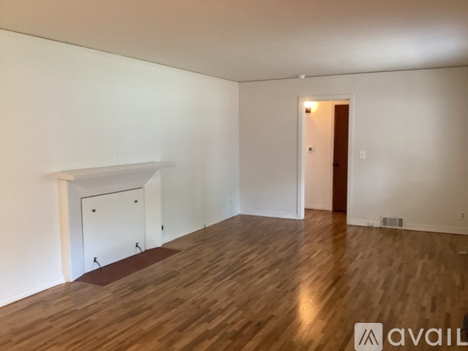 A room with wooden flooring and a white fireplace.