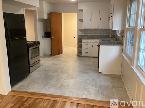 A kitchen with a black fridge and a wooden door.