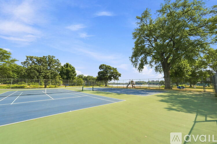 A tennis court surrounded by trees and a fence.