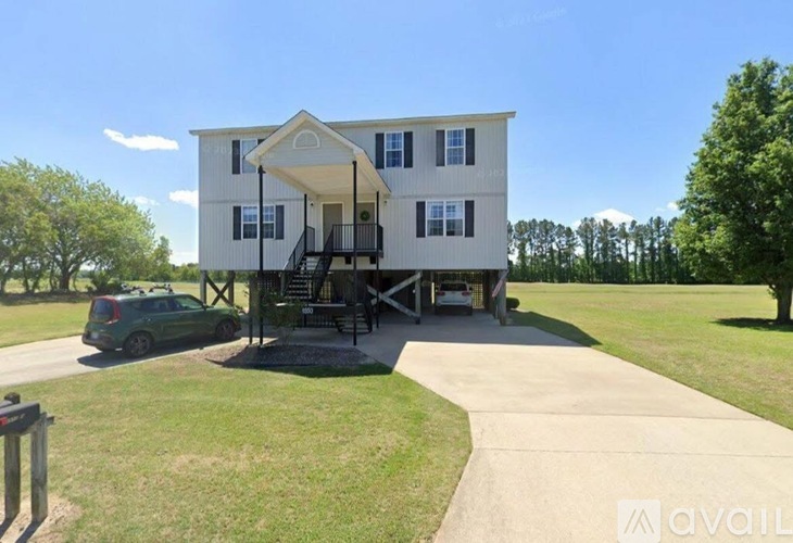 A two-story house with a porch and a car parked in front.
