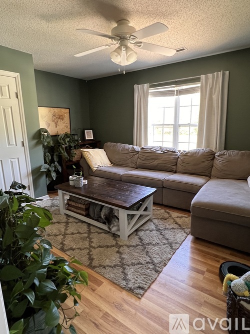 A living room with a couch, a coffee table, and a ceiling fan.
