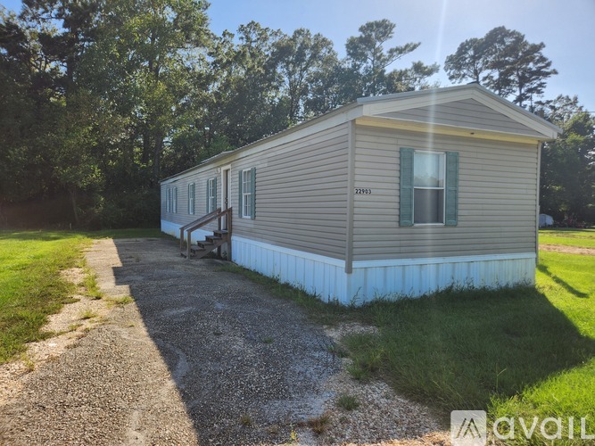 A mobile home with a porch and a gravel driveway.