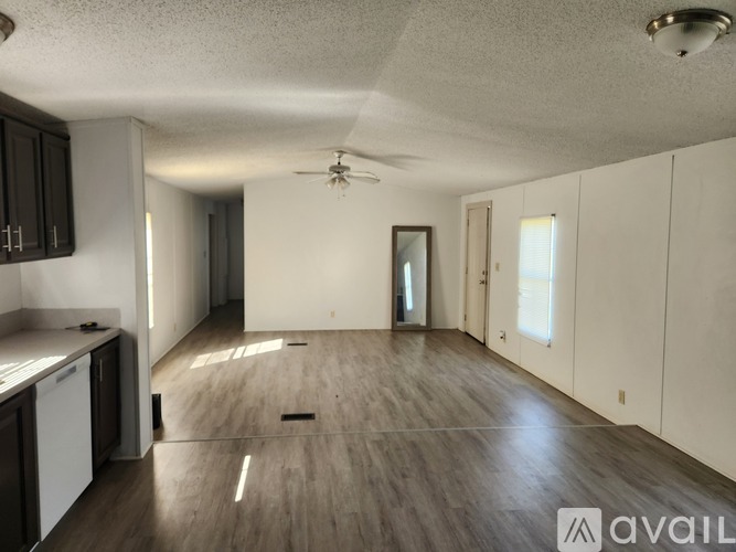 A spacious room with wooden flooring and a ceiling fan.