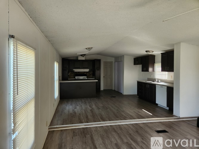 A spacious, empty room with wooden flooring and white walls.