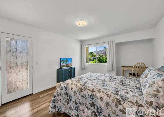 A bedroom with a large bed and a view of the outdoors through the window.