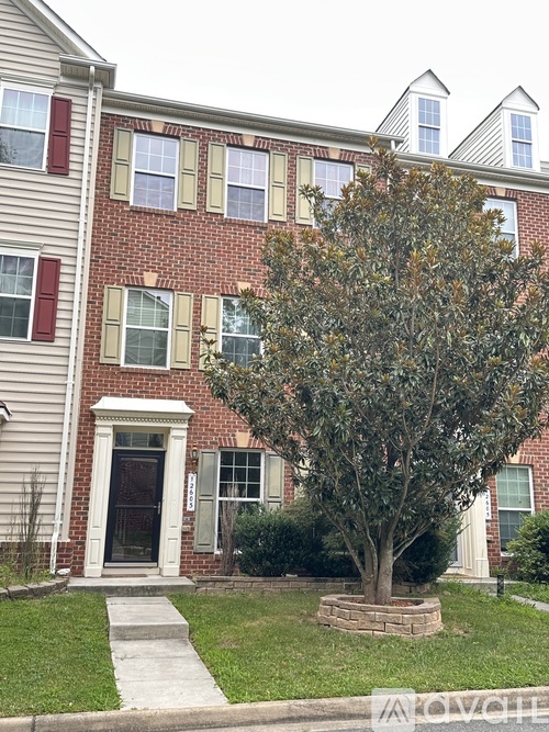 A tree in front of a brick building with a white door.