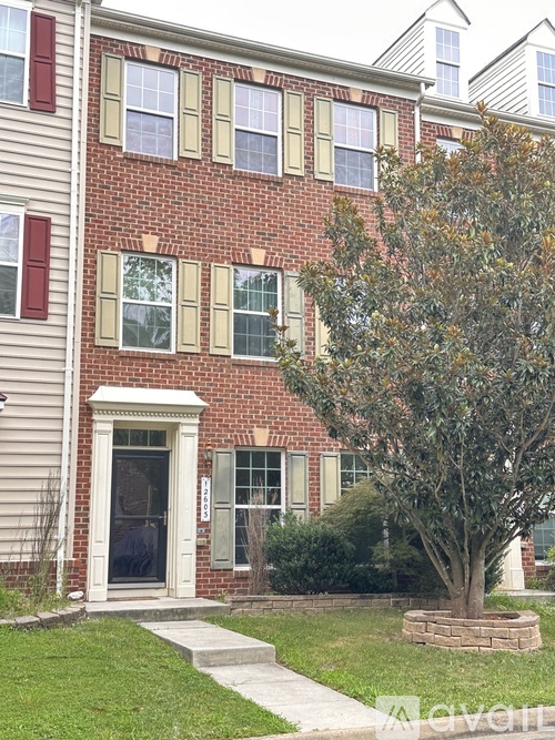 A red brick house with a tree in front.