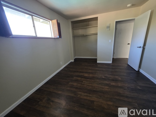 A room with wooden flooring and a window with blinds.