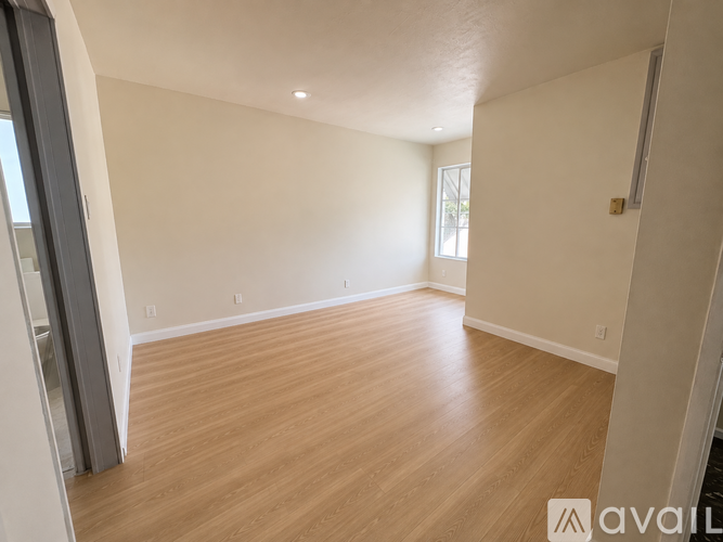 A spacious room with wooden flooring and white walls.