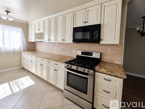 A kitchen with white cabinets and a granite countertop.