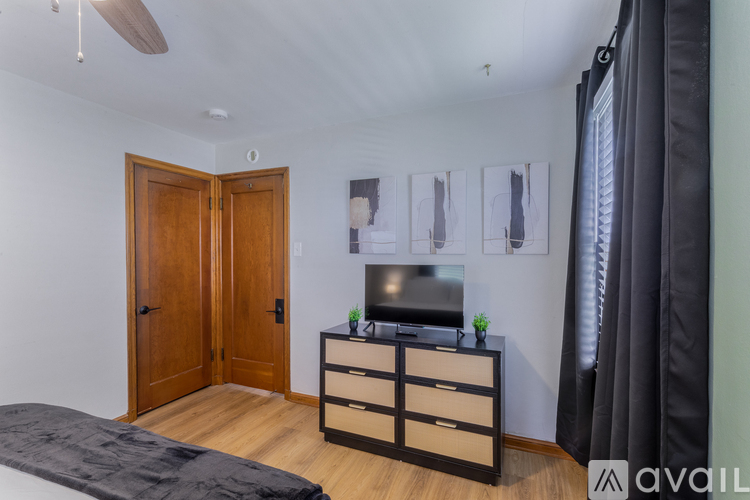 A bedroom with a bed, a dresser with a television on top, and a ceiling fan.