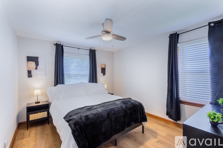 A bedroom with a bed, nightstand, and window with blinds.