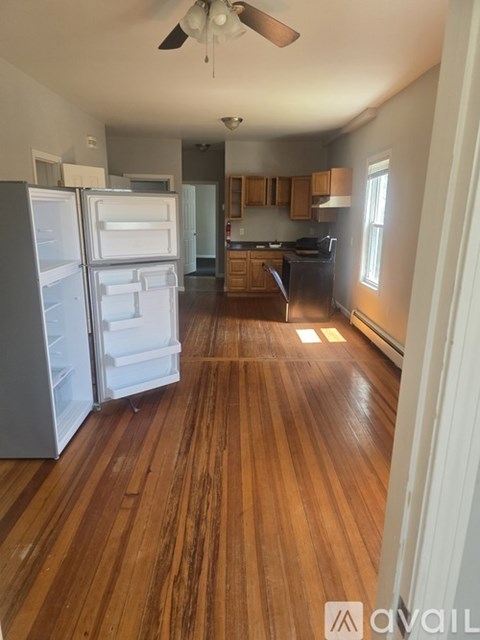 A kitchen with a refrigerator and wooden floors.