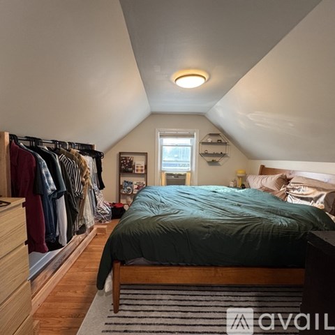 A bedroom with a bed, a window, and a clothing rack.